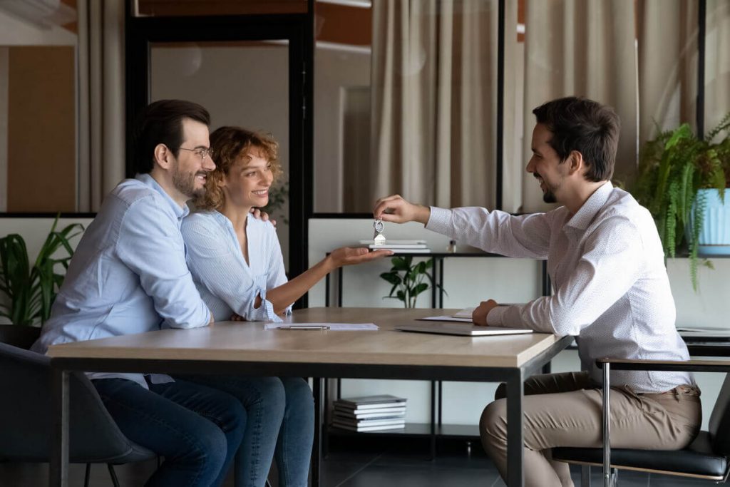 Realtor shaking hands with clients after purchasing home